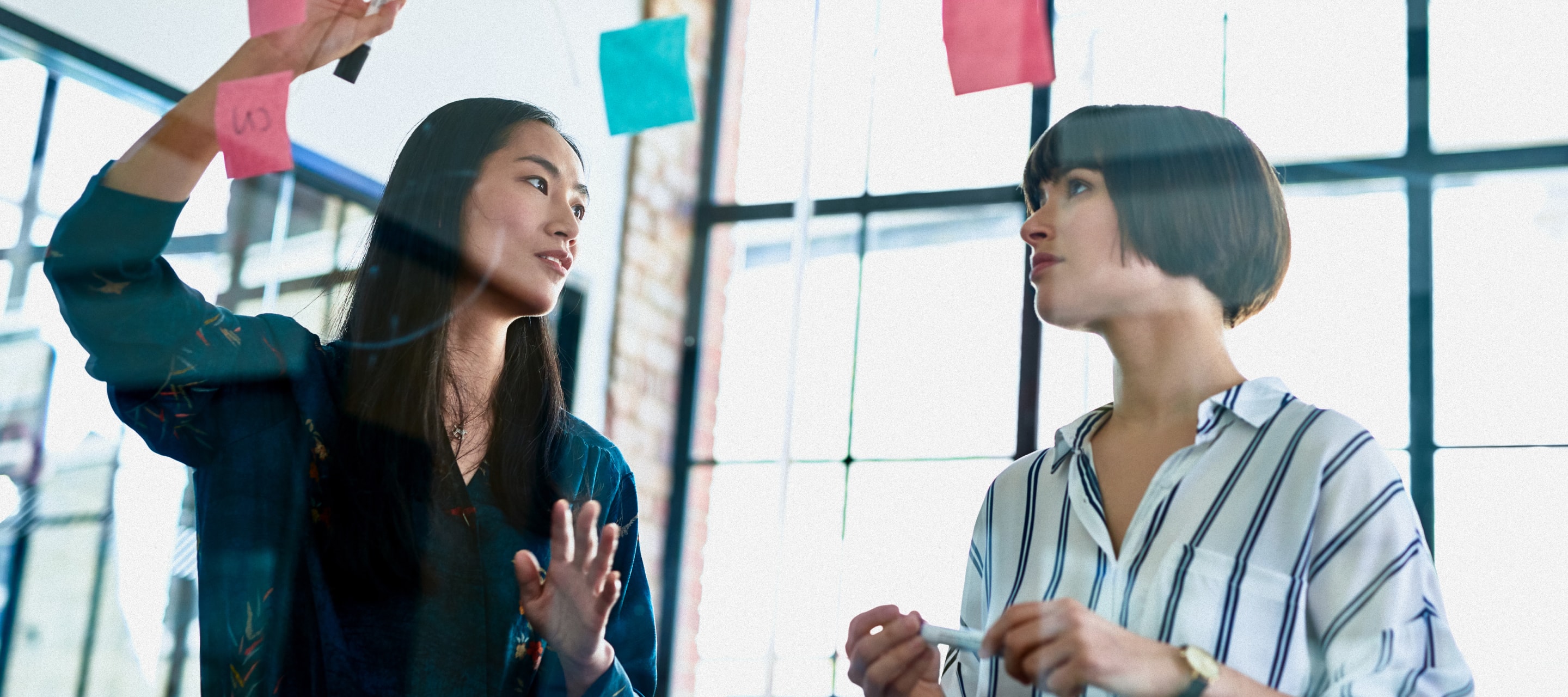 Low angle view of two women colleagues in a workplace discussion.